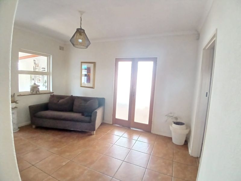 A bright living room featuring tiled flooring, a pendant light fixture, and double glass doors providing natural light and access to the exterior.