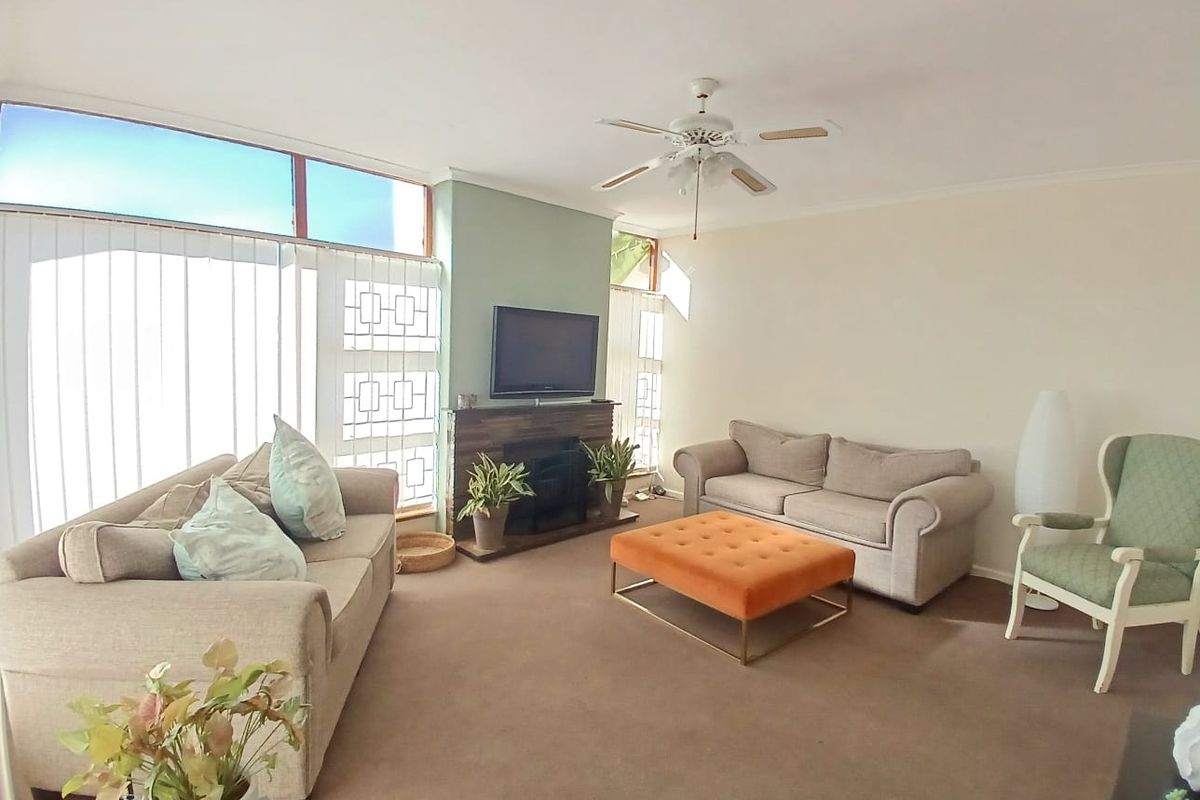A spacious living room featuring a built-in fireplace, ceiling fan, and large windows that provide ample natural light.