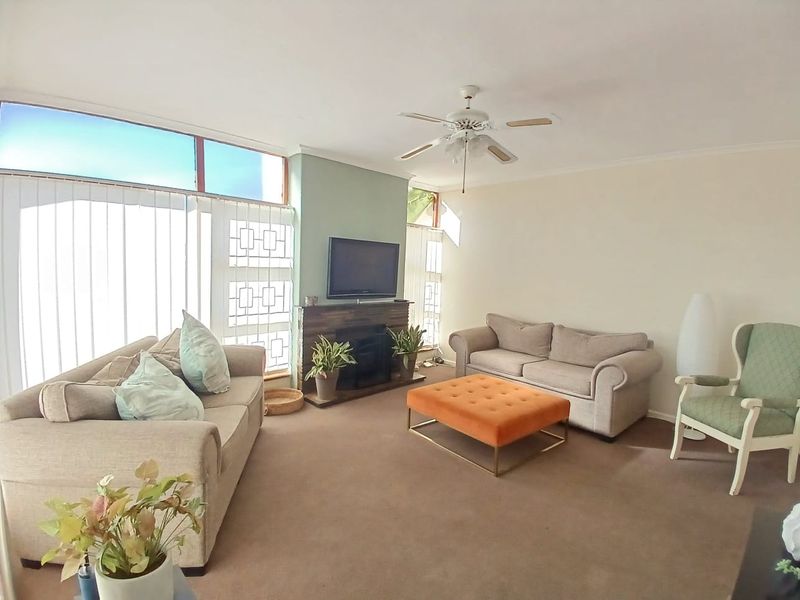 A spacious living room featuring a built-in fireplace, ceiling fan, and large windows that provide ample natural light.