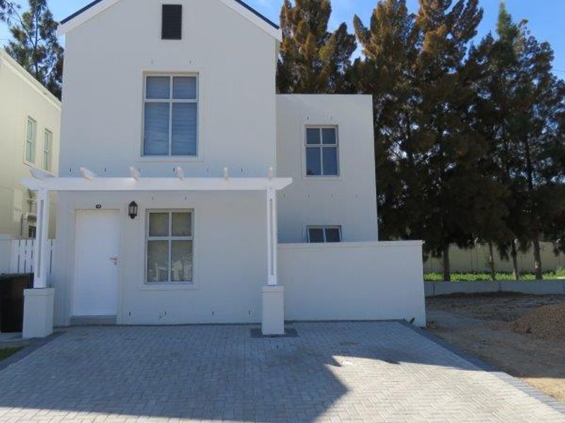 Front elevation of a modern two-story house featuring a paved driveway, a white pergola, and clean exterior finishes.