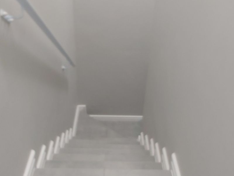 A view looking down a staircase featuring neutral walls, white skirting boards, and a simple handrail.