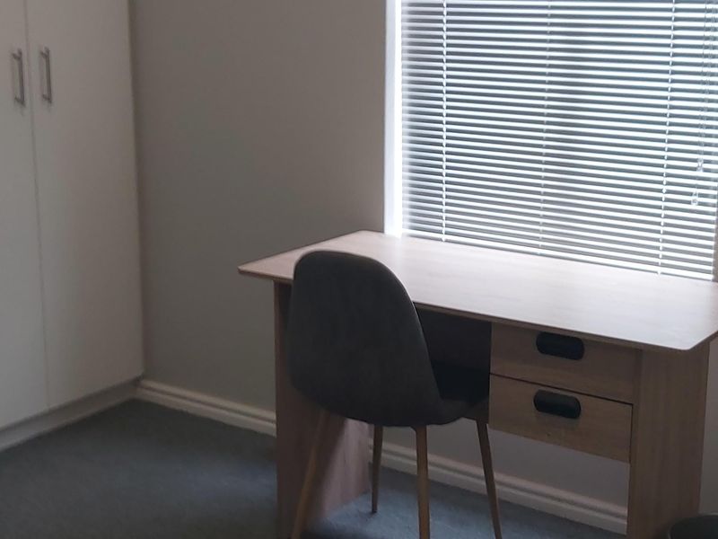 A bedroom featuring a built-in wardrobe and a window fitted with venetian blinds.