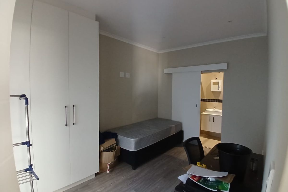 A bedroom featuring built-in wardrobes, laminate flooring, and an en-suite bathroom with a sliding door entrance.
