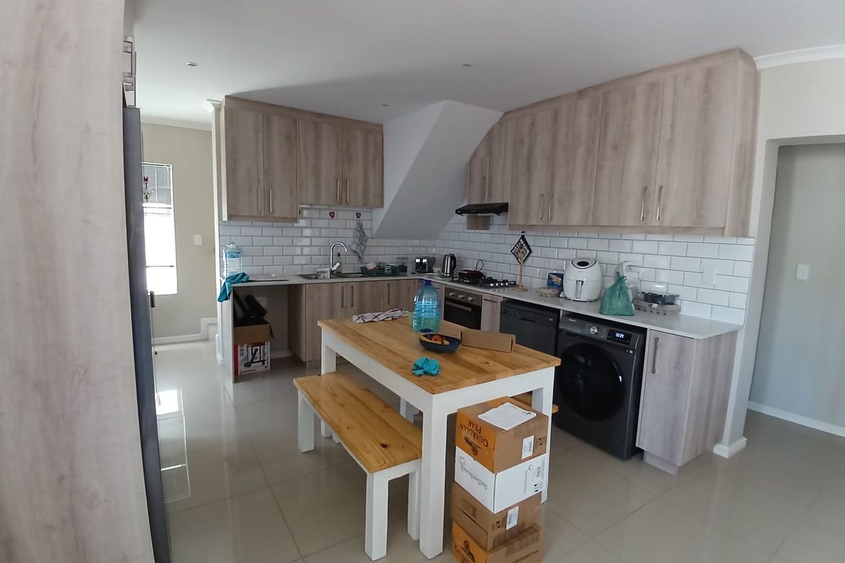 Modern kitchen featuring light wood-grain cabinetry, subway tile backsplash, integrated appliances, and tiled flooring, offering a functional and contemporary cooking space.