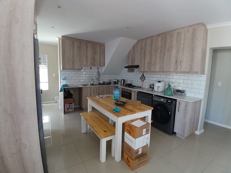Modern kitchen featuring light wood-grain cabinetry, subway tile backsplash, integrated appliances, and tiled flooring, offering a functional and contemporary cooking space.