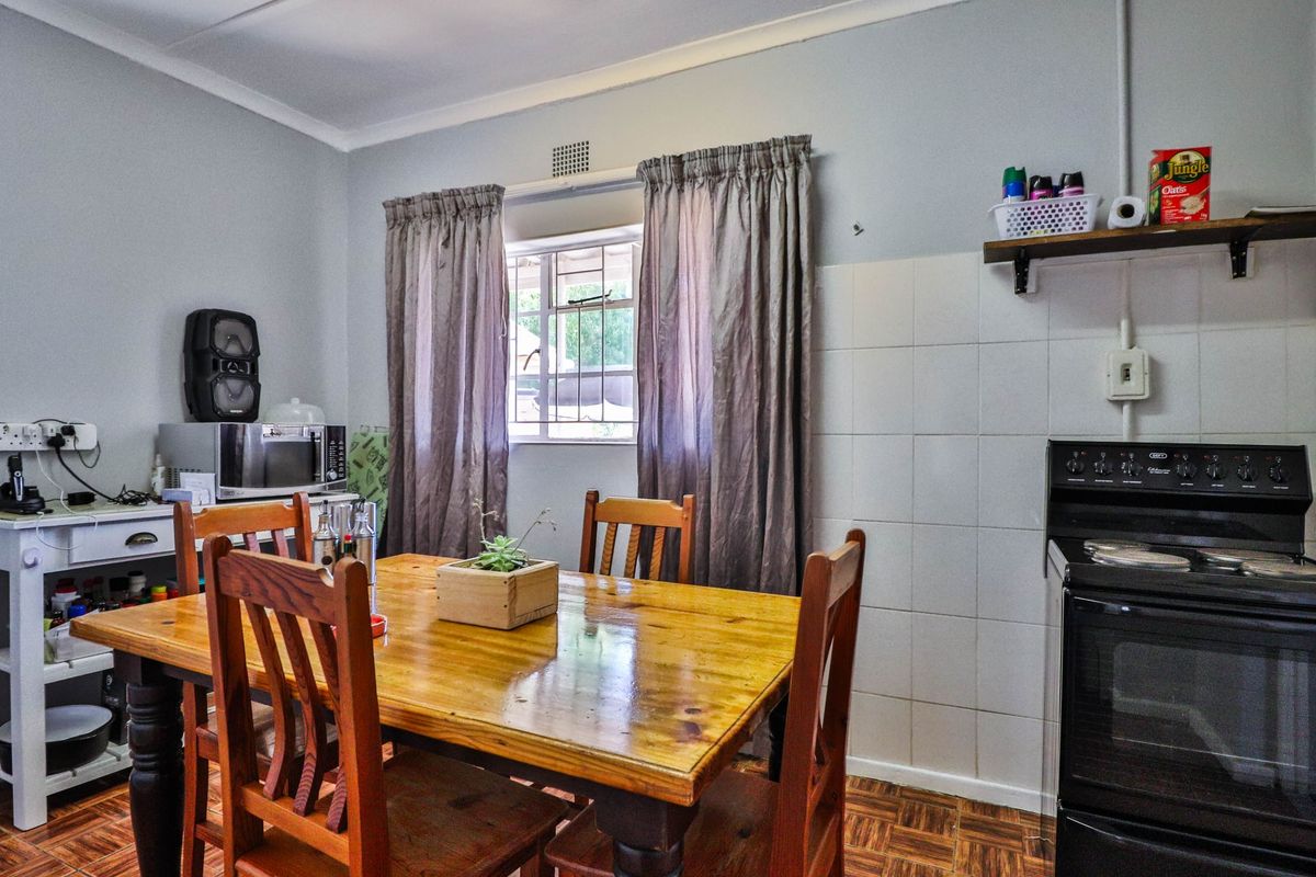 A functional kitchen area featuring parquet flooring, a tiled splashback, and a freestanding stove, with a window providing natural light.