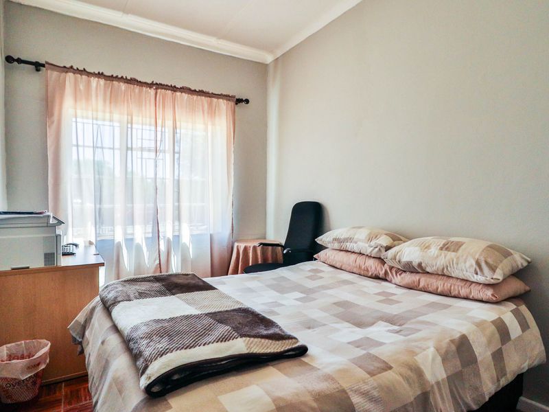 A functional bedroom featuring neutral wall finishes, a window with security bars, and decorative ceiling cornicing.