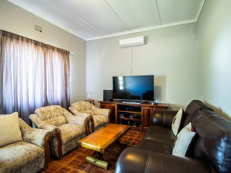 A comfortable living room featuring classic parquet flooring, neutral wall finishes, and a wall-mounted air conditioning unit.