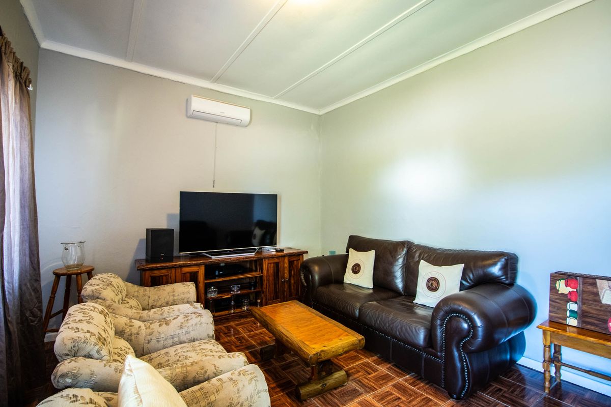 A comfortable living room featuring parquet flooring, a wall-mounted air conditioning unit, and neutral wall finishes.