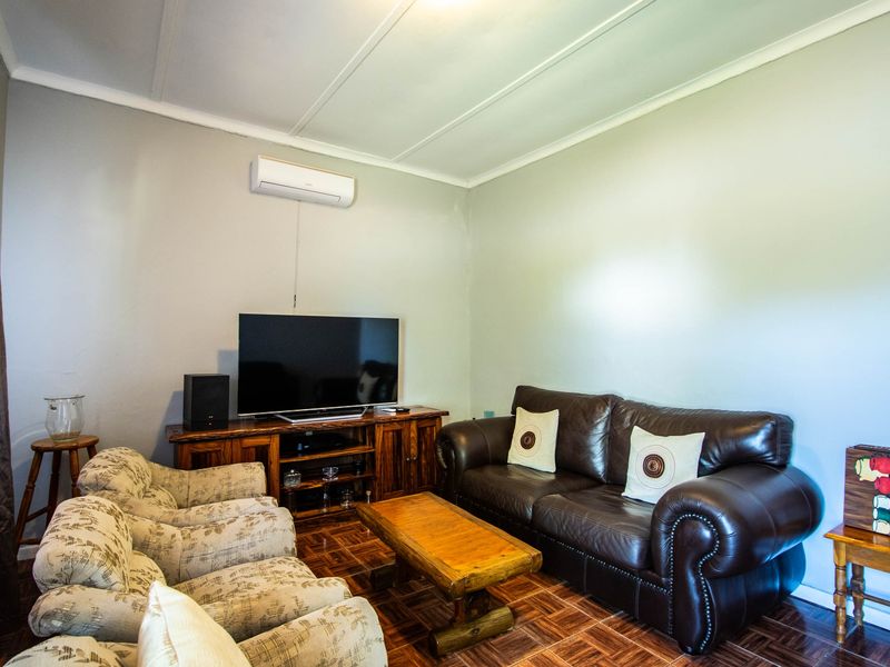 A comfortable living room featuring parquet flooring, a wall-mounted air conditioning unit, and neutral wall finishes.