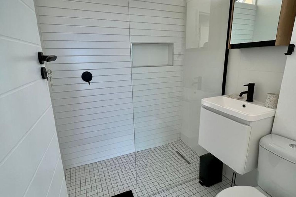 Modern bathroom featuring a walk-in shower with a glass screen, wall-mounted vanity, and contemporary black fixtures.