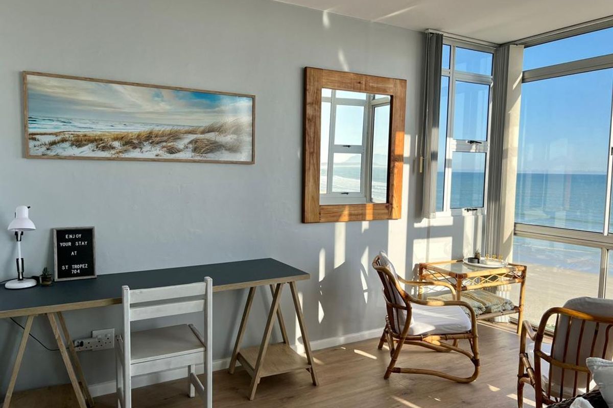 Bright living area featuring floor-to-ceiling windows with expansive ocean views and modern wood-look flooring.