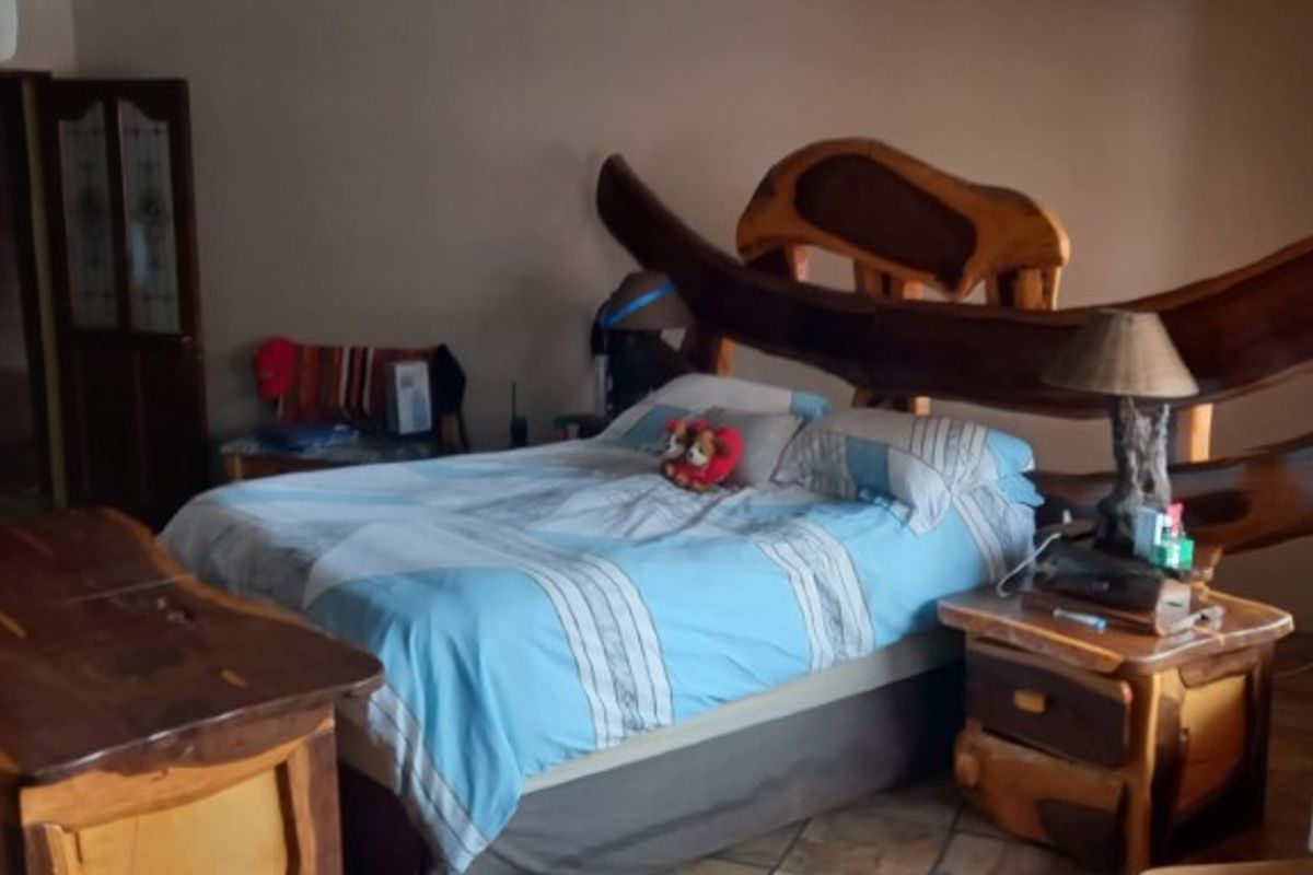 A bedroom featuring tiled flooring, wooden window blinds, and built-in cupboards.