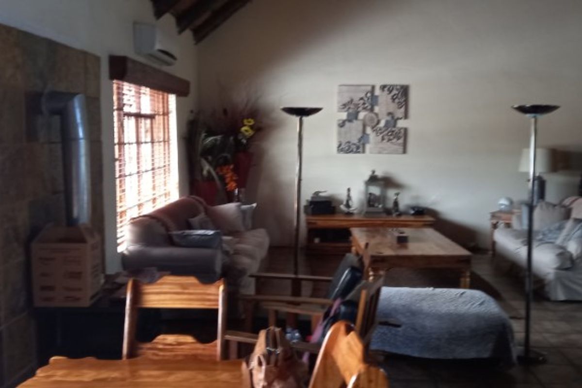 Spacious living area featuring a vaulted ceiling, exposed brick fireplace, and tiled flooring, creating a warm and rustic atmosphere.