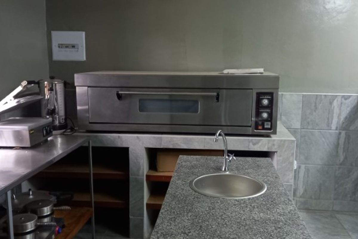 A functional commercial-style kitchen area featuring a built-in stainless steel oven, granite countertop, and integrated prep sink.