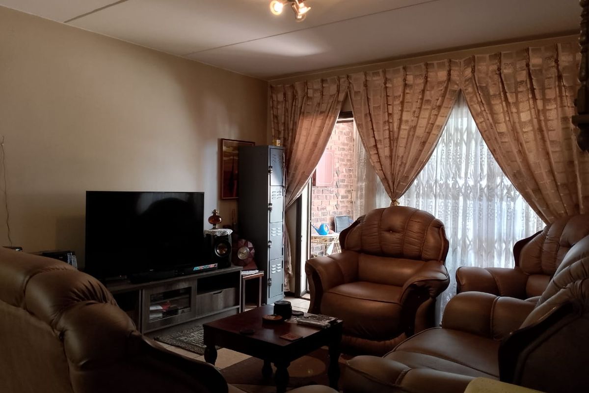 A comfortable living room featuring a sliding glass door with security gate, providing access to the outdoor area.