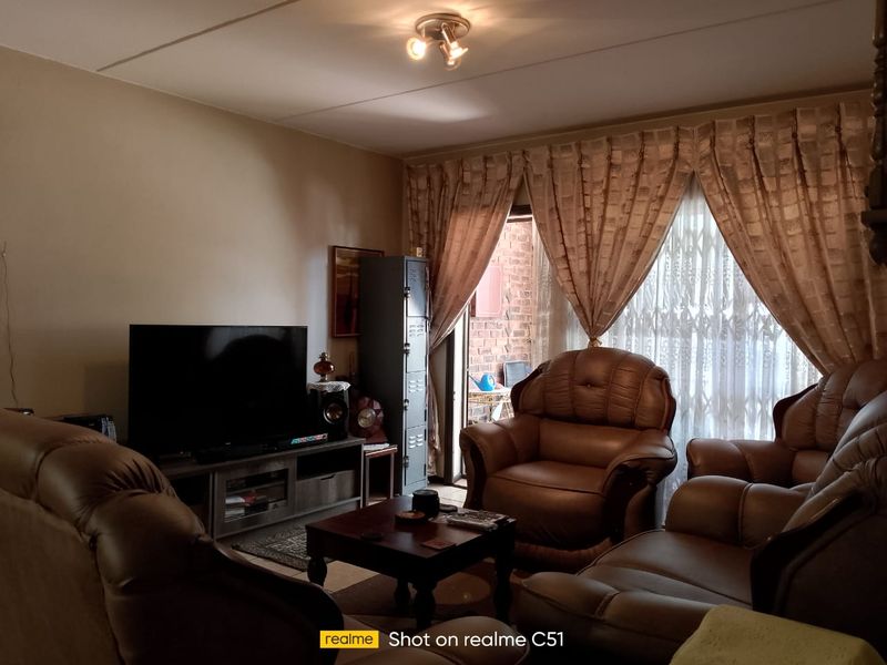 A comfortable living room featuring a sliding glass door with security gate, providing access to the outdoor area.