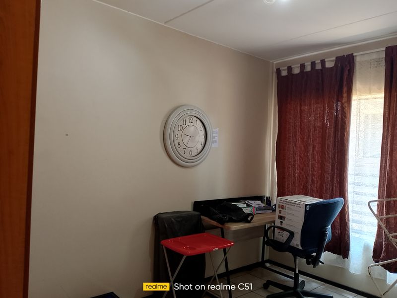A functional bedroom space featuring tiled flooring and window treatments, suitable for use as a bedroom or home office.