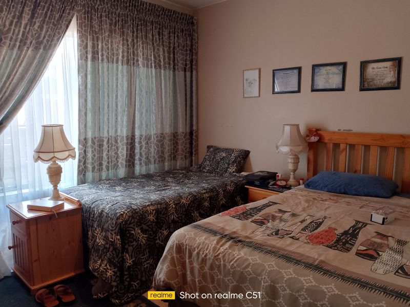 A functional bedroom featuring a window with curtains and space for multiple beds.