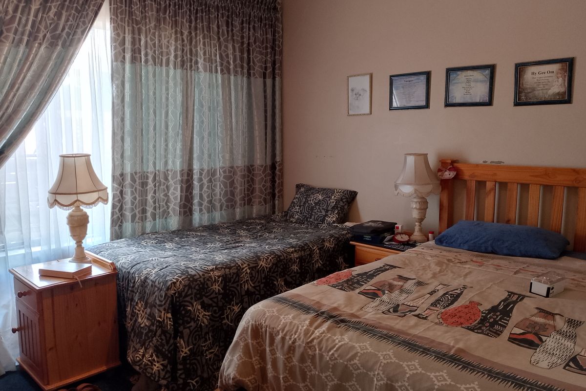 A functional bedroom featuring a window with curtains and space for multiple beds.