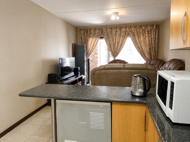 Open-plan living area featuring a kitchen breakfast bar with granite countertops, tiled flooring, and direct access to an outdoor patio area.
