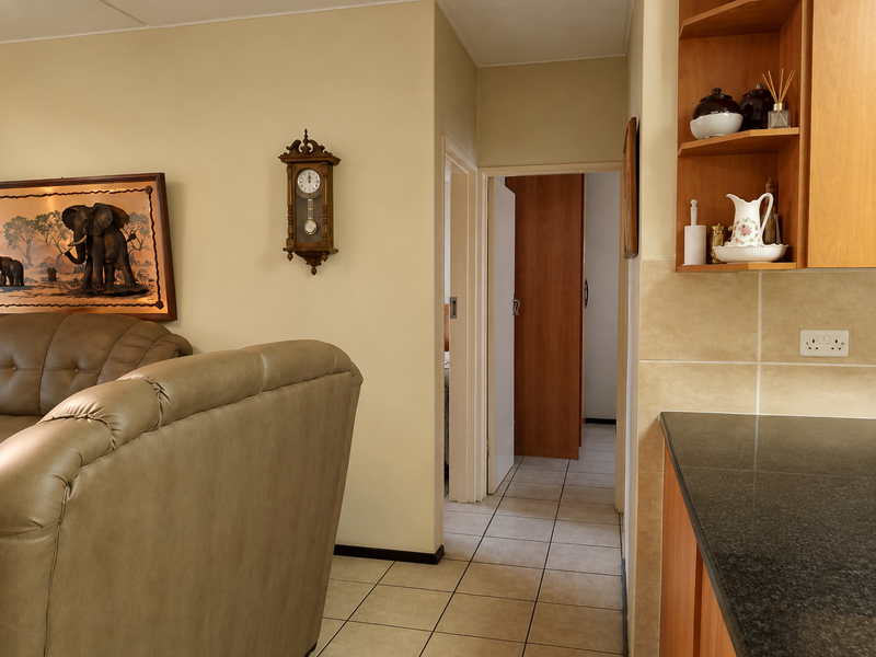 Open plan living area featuring tiled flooring, kitchen cabinetry with granite countertops, and a seamless transition to the hallway and bedroom.