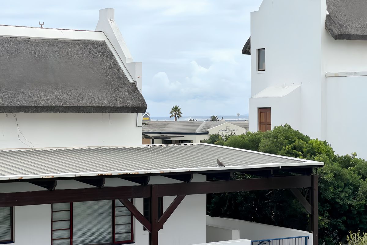 Exterior view of the property featuring a combination of thatched and corrugated metal roofing with a timber pergola structure.