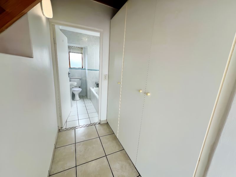 A functional hallway featuring built-in storage cupboards and tiled flooring, providing direct access to an adjacent bathroom.