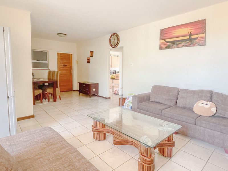 Open plan living area featuring neutral tiled flooring and access to adjacent rooms, providing a functional and versatile living space.