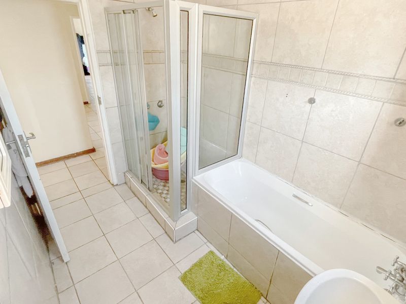 A functional bathroom featuring a separate shower enclosure, a bathtub, and neutral wall and floor tiling.