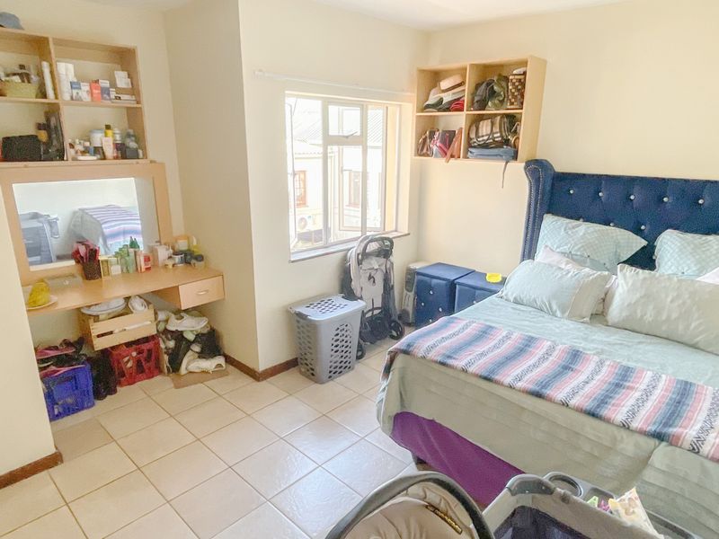 A bedroom featuring tiled flooring, built-in vanity with shelving, and a window providing natural light.