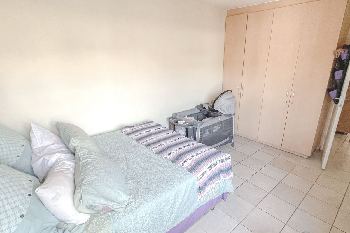A functional bedroom featuring neutral wall finishes, tiled flooring, and a built-in wardrobe for storage.