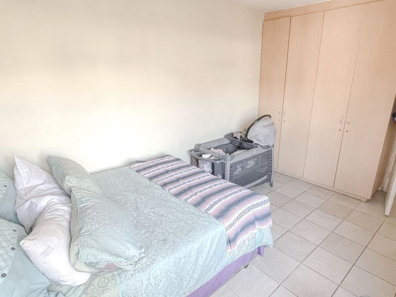 A functional bedroom featuring neutral wall finishes, tiled flooring, and a built-in wardrobe for storage.