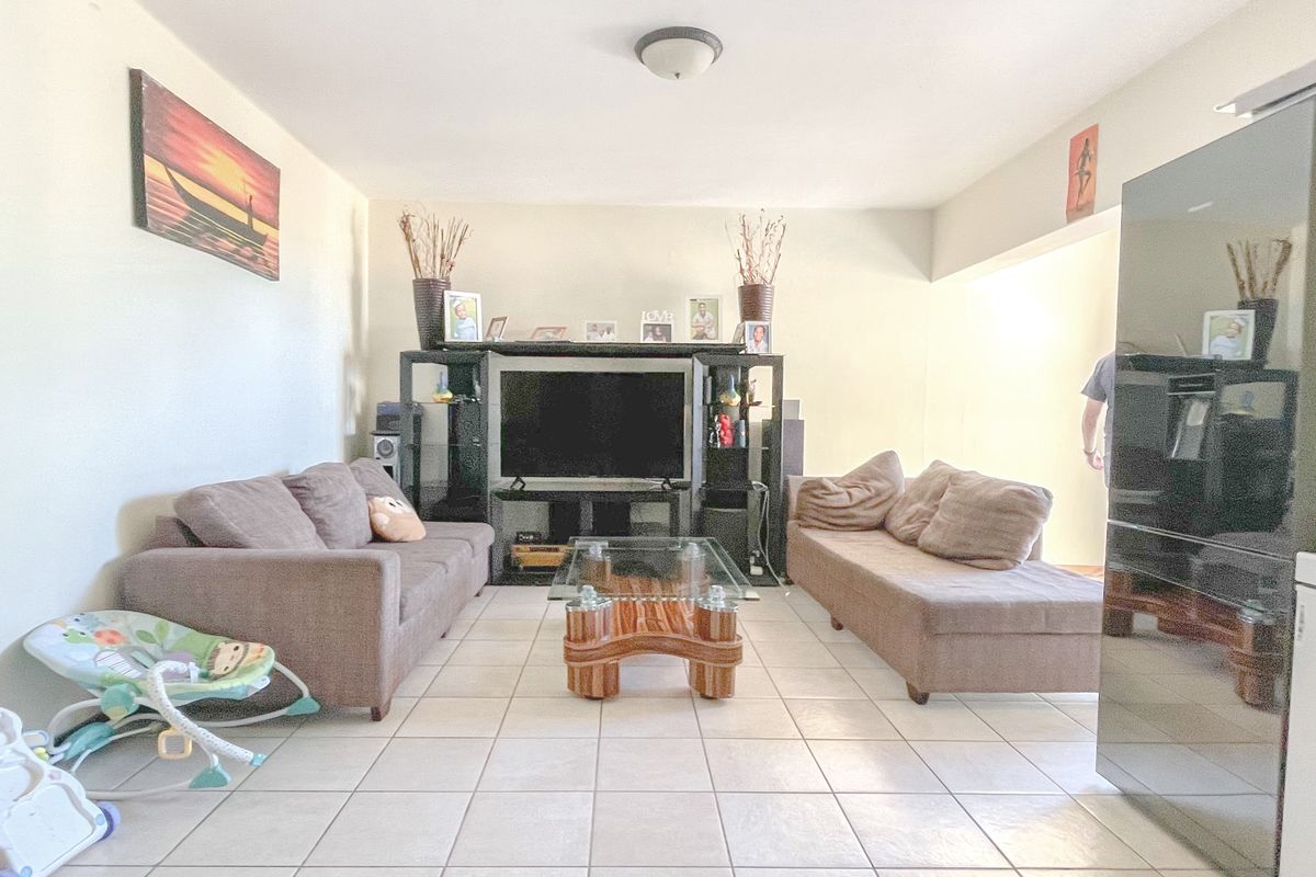 A living room area featuring neutral wall finishes and ceramic floor tiles, providing a functional space for relaxation.