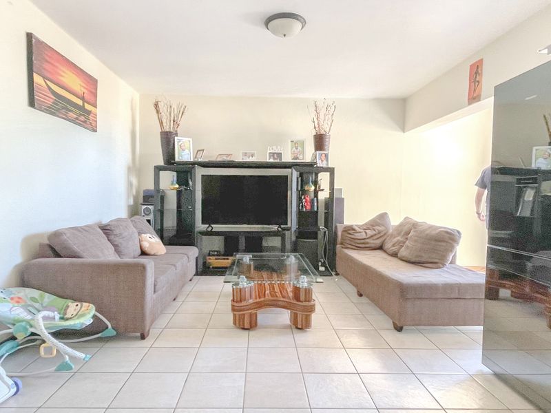 A living room area featuring neutral wall finishes and ceramic floor tiles, providing a functional space for relaxation.