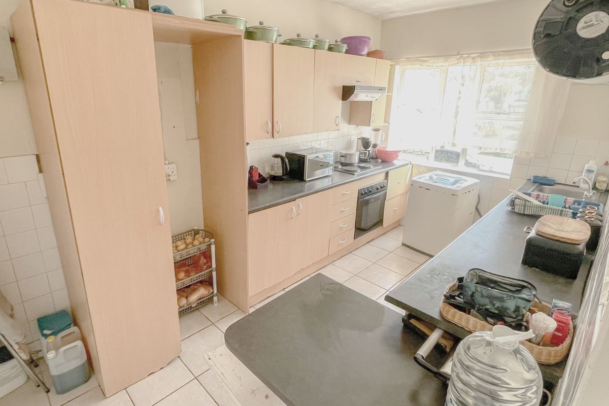 A functional kitchen featuring light wood-tone cabinetry, tiled flooring, a built-in oven, and a double sink with ample counter space.