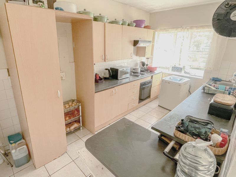 A functional kitchen featuring light wood-tone cabinetry, tiled flooring, a built-in oven, and a double sink with ample counter space.