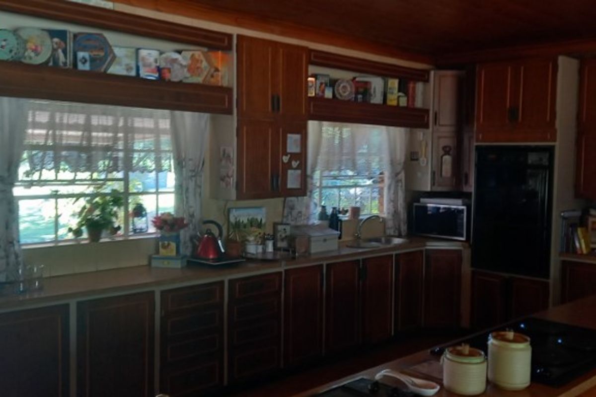 A traditional kitchen featuring extensive dark wood cabinetry, built-in oven, and a functional layout with ample counter space and natural light.