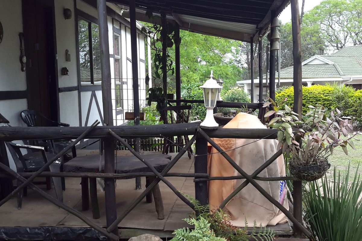 A rustic covered patio area featuring timber railings and posts, overlooking a garden space, offering potential for outdoor living enhancement.
