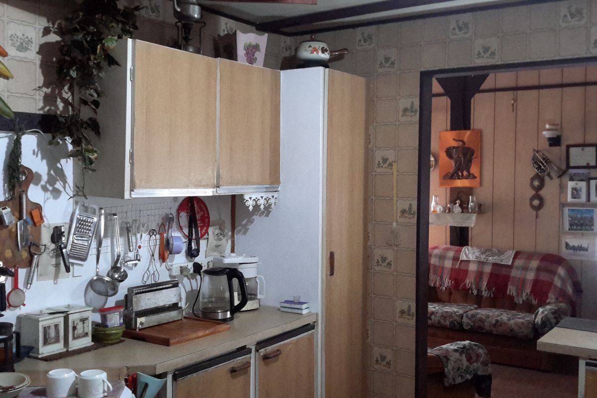 A dated kitchen area featuring original cabinetry and tiled wall finishes, offering significant potential for modernization and renovation.