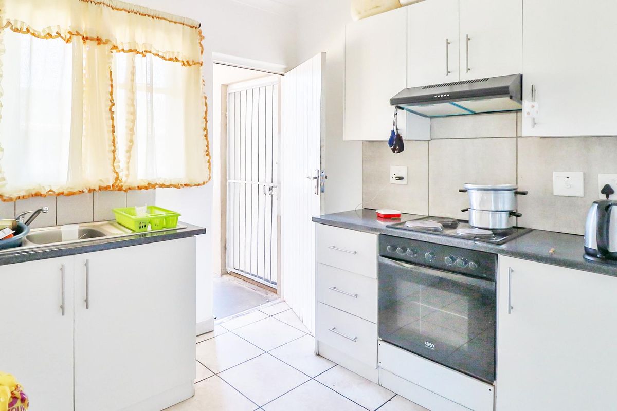 A functional kitchen featuring white cabinetry, a built-in oven and stove, tiled flooring, and direct access to an exterior security gate.