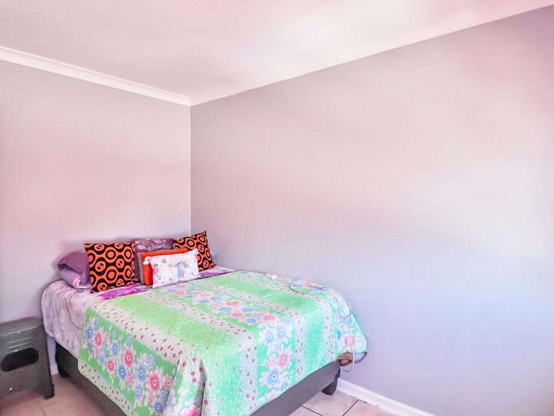 A simple bedroom featuring neutral wall paint, cove cornicing, and tiled flooring.