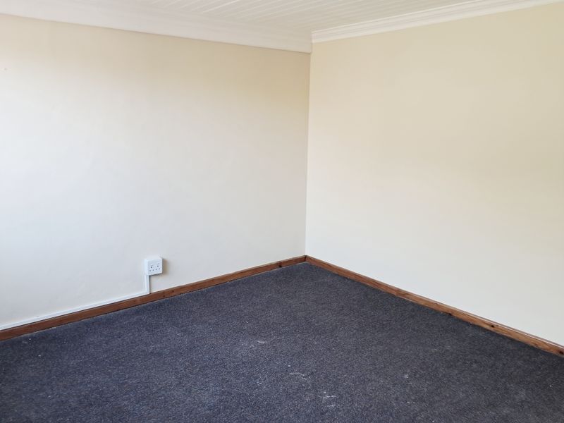 A clean, empty bedroom featuring neutral wall tones, carpeted flooring, and timber skirting boards, providing a versatile blank canvas for interior design.