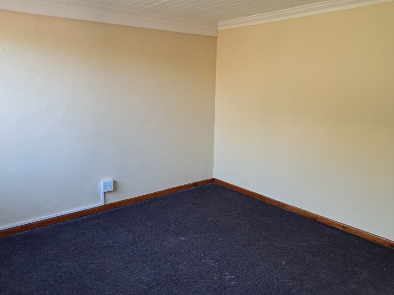 An empty bedroom featuring neutral walls, carpet flooring, timber skirting boards, and a coved ceiling.