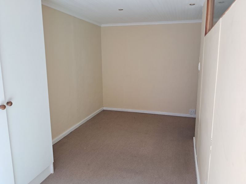 An empty bedroom featuring neutral wall tones, carpeted flooring, and a built-in cupboard with recessed ceiling lighting.