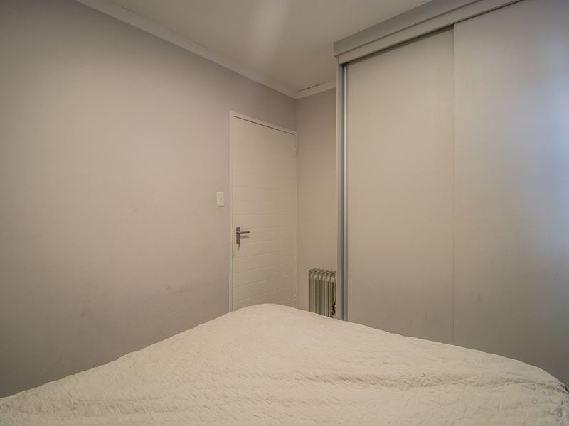 A bedroom featuring a built-in sliding door wardrobe and a wall-mounted radiator, finished with neutral wall tones.