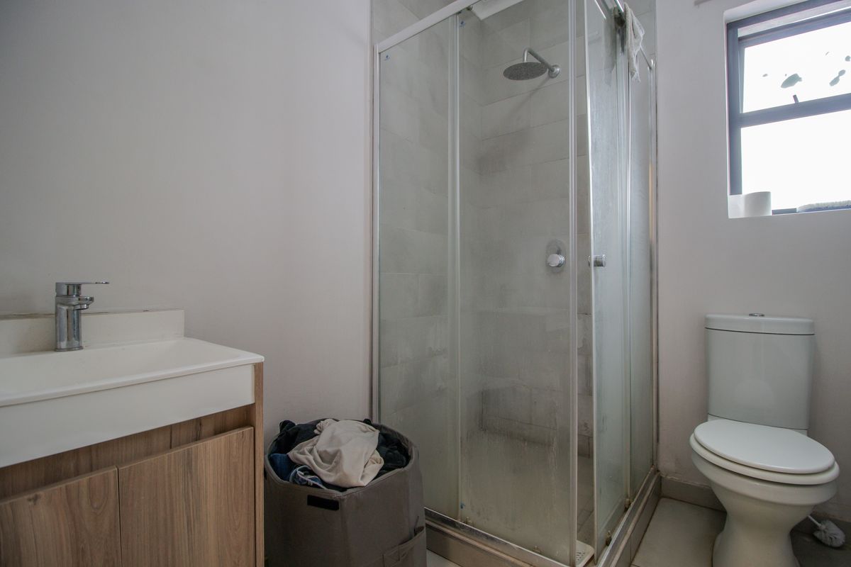 A functional bathroom featuring a shower enclosure, a modern vanity with basin, and a standard toilet.