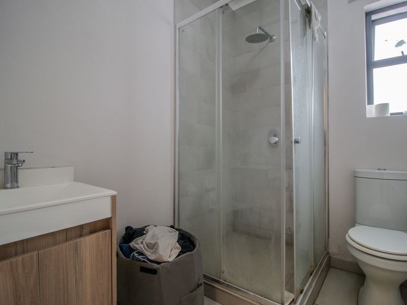 A functional bathroom featuring a shower enclosure, a modern vanity with basin, and a standard toilet.