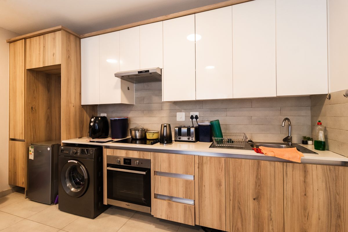 Modern kitchen featuring wood-grain and white cabinetry, integrated oven and hob, tiled backsplash, and durable tiled flooring.