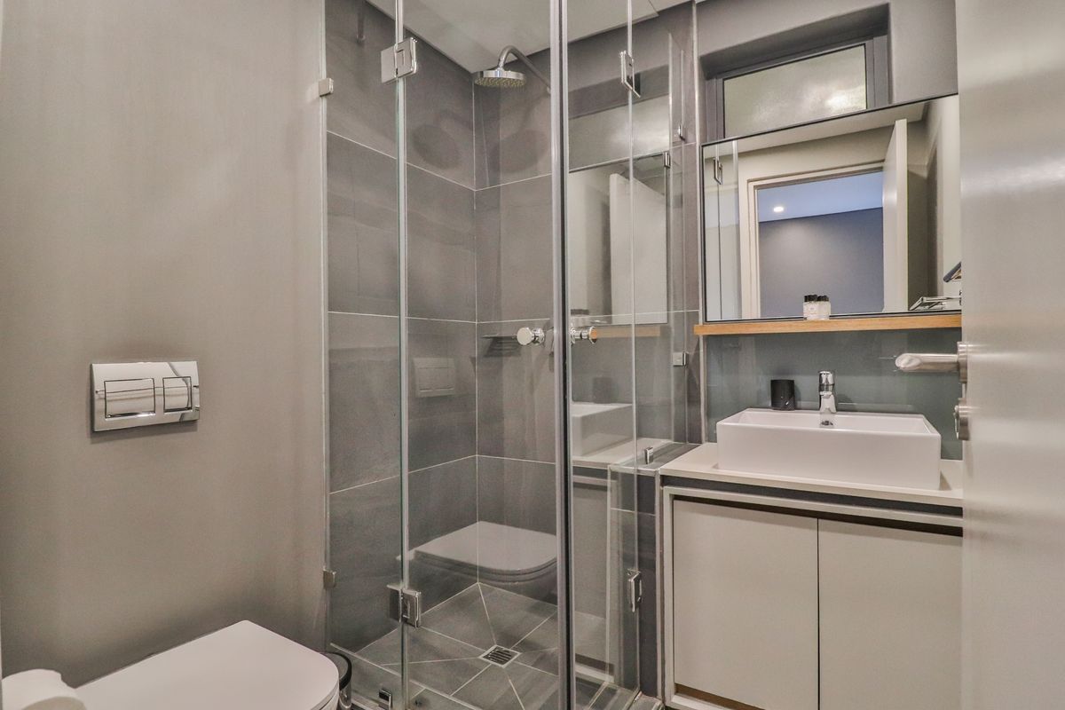 Modern bathroom featuring a glass-enclosed shower with rain head, wall-mounted toilet, and a sleek vanity with a vessel sink.